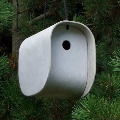 Swisspearl Birdie Vogelhaus hängend in einer immergrünen Tanne.