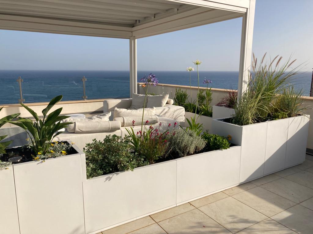 Weiße Domino-Pflanzgefäße auf der Terrasse mit Blick aufs Meer