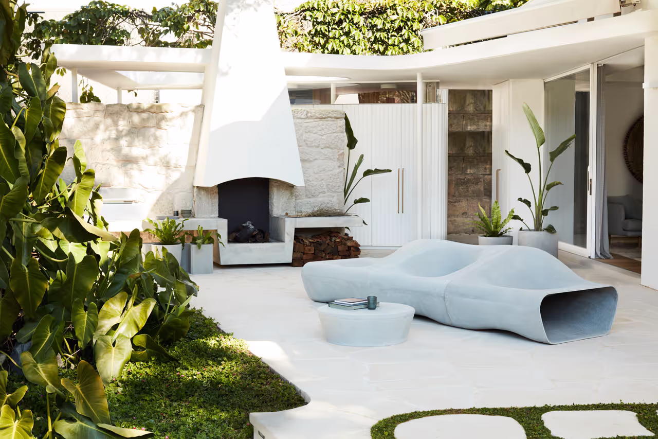 Swisspearl Dune‑Sofa und Porto‑Tisch im modernen Garten neben einem Kamin
