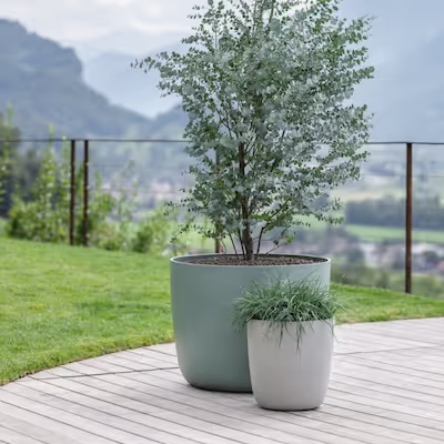Zwei Swisspearl Kyoto Pflanzgefäße mit Baum und Pflanze auf dem Balkon mit Bergblick.