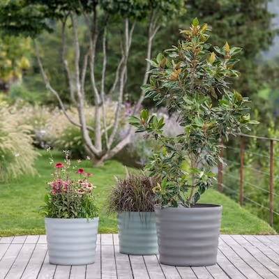 Drei Swisspearl Maia Pflanzgefäße im Garten.